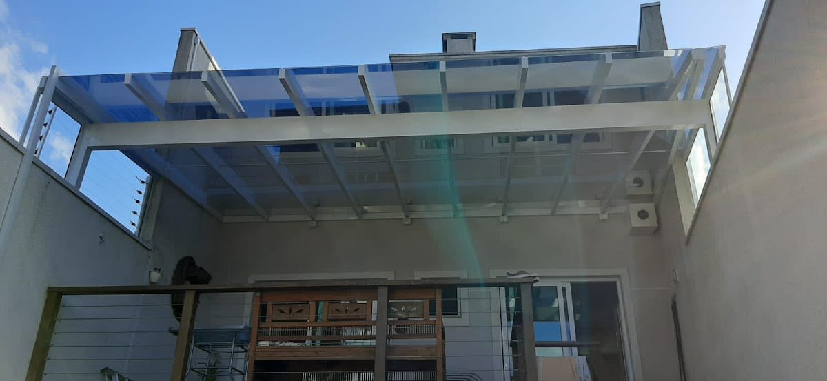 Cobertura de vidro laminado instalada sobre deck de madeira nos fundos de uma casa